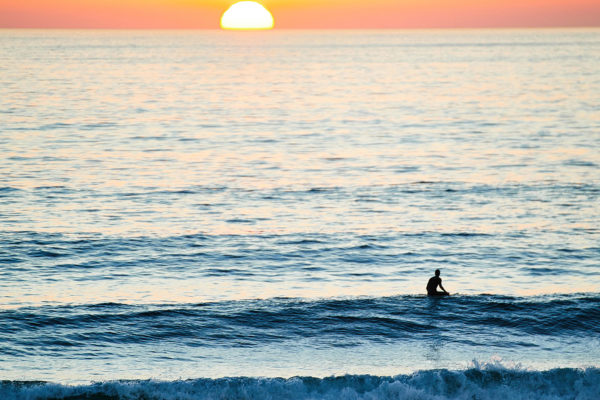 man in ocean at sunset